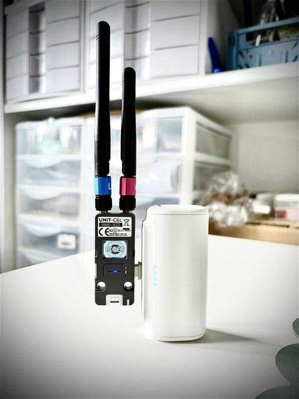 A Biper module with two antennas and its screen on, connected to a power bank.